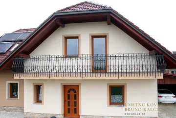 Trebušasta ograja čez vso širino z občutkom za domačnost narejene hiše, nad kamnito oblogo pritličja