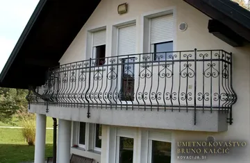 Kovana ograja s manjšim trebuhom na rahlo zaobljenem balkonu, montirana na čelo balkona