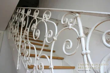Kovana stopniščna ograja iz okroglega paličnega jekla v beli barvi in zlato patino