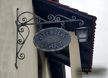 Izvesek za atelje z ovalno reklamno tablo in kovano laterno
