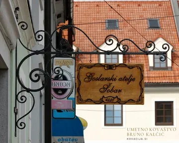 Kovan nosilec za leseno reklamno tablo goslarskega ateljeja