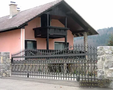 Klasična masivna kovana ograja in vrata na kamnitem zidu
