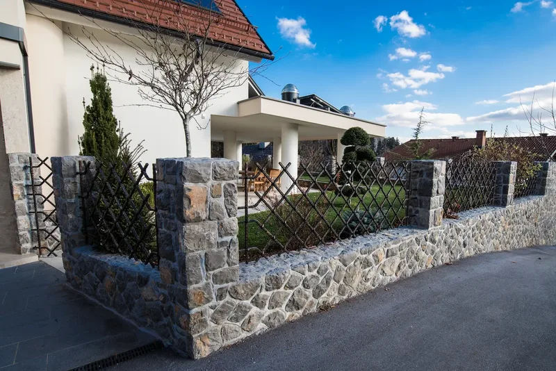 Moderna kovana dvoriščna vrata in ograja med kamnitimi stebri, Ljubljana