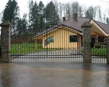 Široka obokana moderna kovana vrata z kovanimi figurami in valovitim vzorcem po ideji projektanta
