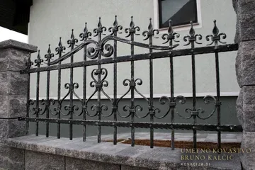 Ograja z bogato okrašenimi loki na zidu iz lomljenih blokov